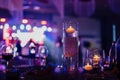 Banquet table decorated with burning candles in glass vases in restaurant hall. In the background party with silhouettes Royalty Free Stock Photo