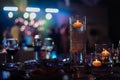 Banquet table decorated with burning candles in glass vases in restaurant hall. In the background party with silhouettes Royalty Free Stock Photo
