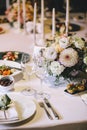 Banquet table for dinner decorated with flower bouquets of dahlia and white candles. On the table, glasses, cutlery and white plat Royalty Free Stock Photo