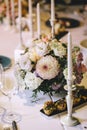 Banquet table for dinner decorated with flower bouquets of dahlia and white candles. On the table, glasses, cutlery and white plat Royalty Free Stock Photo