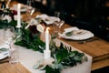 Banquet table setting. Plates, forks, candles on wooden table with nice decoration. Cutlery and wine glasses. Restaurant cozy inte Royalty Free Stock Photo