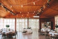 Banquet wooden hall for a rustic wedding with round decorated tables, Viennese chairs with flowered leaves and Royalty Free Stock Photo