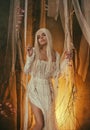 Banshee fairy. Pale blonde girl in white vintage dress. Seductive princess, with sexy, long legs posing against the Royalty Free Stock Photo