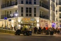 Fully occupied tables and chairs at a restaurant in evening. In the foreground you can see a golf cart for bringing guests to thei