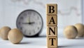 BANT - acronym on wooden cubes on graph, clock and wooden balls background