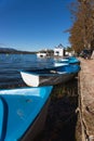 BANYOLES, SPAIN - 11 OCTOBER 2020 : Blue boats for renting and People walking by the lake of Banyoles in Catalonia. Wearing masks