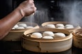 bao bun being carefully separated from its bamboo steamers, with hint of steam still visible