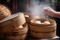 bao bun being carefully separated from its bamboo steamers, with hint of steam still visible