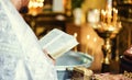 Baptism priest reading from bible during ceremony holding cross. Royalty Free Stock Photo