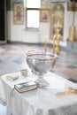 Baptismal font with wax candles and cross are on the table near Holy Bible Royalty Free Stock Photo