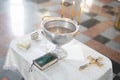 Baptismal font with wax candles and cross are on the table near Holy Bible Royalty Free Stock Photo