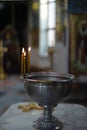 Baptismal font with wax candles and cross are on the table Royalty Free Stock Photo