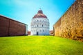 Baptistery of St. John on Square of Miracles with brick wall, famous Leaning tower of Pisa with green lawn in Pisa, Tuscany, Italy