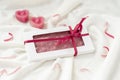 Bar of chocolate with hearts tied with a ribbon with a bow lies on a light background next to a pair of candles