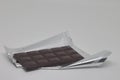 A bar of chocolate lies on a shiny silver wrapper, a delicacy sweetness Royalty Free Stock Photo