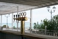 Bar counter with beer column with three taps in the beach bar on the background of the sea lights fencing and greenery