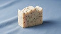 A bar of handcrafted soap rests on a fabric surface with a soft blue hue Royalty Free Stock Photo