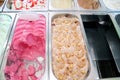 Bar with many flavors of delicious ice cream for sale. Fridge with creamy of hazelnut flavors, raspberry and cherry in container.