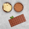 Bar of milk chocolate, cocoa powder, cocoa butter and mint on gray stone background Royalty Free Stock Photo
