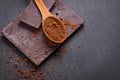 Bar of natural chocolate and cocoa powder in a wooden spoon on black stone bacgkround Royalty Free Stock Photo