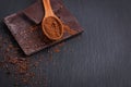 Bar of natural chocolate and cocoa powder in a wooden spoon on black stone bacgkround Royalty Free Stock Photo