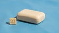 Bar of soap rests on a blue surface. Beside it a small cube with Royalty Free Stock Photo