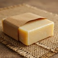 Bar of soap wrapped in brown paper, resting on a piece of burlap fabric. The soap has Royalty Free Stock Photo