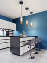 Bar with three chairs in a modern kitchen, a white kitchen island, pendant lights