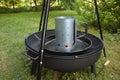 Barbecue charcoal chimney starter on a black tripod swivel grill Royalty Free Stock Photo