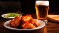 barbecue chicken wings on a plate with a glass of beer on a wooden table