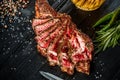 Barbecue dry aged rib of beef with spice, vegetables and a glass of light beer close-up on black wooden background Royalty Free Stock Photo