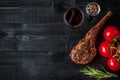 Barbecue dry aged rib of beef with spice, vegetables and glass of red wine close-up on black wooden background Royalty Free Stock Photo