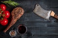 Barbecue dry aged rib of beef with spice, vegetables and glass of red wine close-up on black wooden background Royalty Free Stock Photo