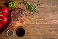 Barbecue dry aged rib of beef with vegetables and glass of red wine close-up on wooden background Royalty Free Stock Photo