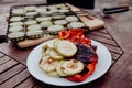 Barbecue fried vegetables laid out on a plate against a barbecue grill Royalty Free Stock Photo