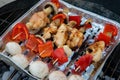 Barbecue in the garden, you can see skewers, chicken and mushrooms and peppers. Metal sheet over heated coals.