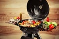 Barbecue grill with meat products and vegetables on background, closeup