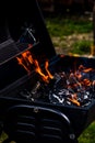 Barbecue grill pit with glowing and flaming hot open fire with red flame, hot charcoal briquettes and embers Royalty Free Stock Photo