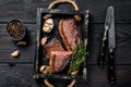 Barbecue Grilled rump cap or brazilian picanha beef meat steak in a wooden tray. Black wooden background. Top view