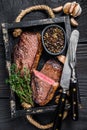 Barbecue Grilled rump cap or brazilian picanha beef meat steak in a wooden tray. Black wooden background. Top view