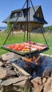 barbecue making outside on real wood fire. Colorful plate with food, cooking in front of wooden house. Grill summer sunny party, Royalty Free Stock Photo