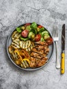 Barbecue plate - chicken breast, yellow zucchini, grilled potatoes and fresh vegetable salad with pesto sauce dressing on a grey Royalty Free Stock Photo