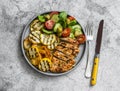 Barbecue plate - chicken breast, yellow zucchini, grilled potatoes and fresh vegetable salad with pesto sauce dressing on a grey Royalty Free Stock Photo