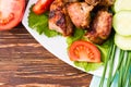 Barbecue on a plate, greens and vegetables on a wooden table Royalty Free Stock Photo