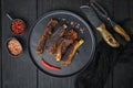 Barbecue pork spare ribs with fruit relish, on plate, with barbeque knife and meat fork, on black wooden table background, top Royalty Free Stock Photo