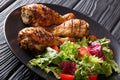 Barbecue serving of grilled chicken drumsticks and fresh vegetable salad closeup. horizontal