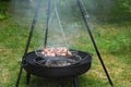 Barbecue shashlik skewers on a black tripod swivel grill in the