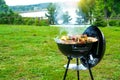 Barbecue time at the nature. BBQ grilling on the shore of a picturesque lake. Royalty Free Stock Photo