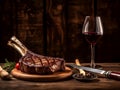 Barbecue Tomahawk Steak served on wooden Cutting Board with spices, rosemary, cherry tomatoes and glass of red wine on a steak