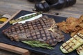 Barbecued t-bone steak seasoned with fresh herbs and marinade served with a cutting board in a steakhouse. Delicious restaurant